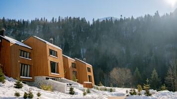 A modern wooden building with multiple windows and a snow-covered landscape.