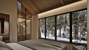 Une chambre avec une grande fenêtre donnant sur une forêt enneigée.