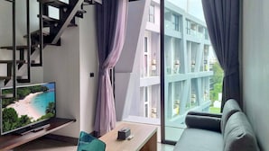 A modern living room with a TV, sofa, and a wooden coffee table. - NaiHarn Duplex with Pool View UTL A310 (Rawai)