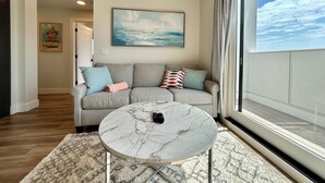 A living room with a grey sofa, a marble coffee table, and a painting on the wall. - The LUX~ 1 Block to the Beach!! (Traverse City)