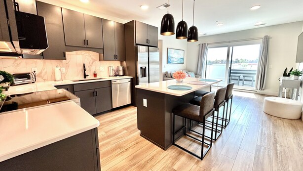 A modern kitchen with a central island, bar stools, and pendant lighting. - The LUX~ 1 Block to the Beach!! (Traverse City)