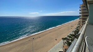 Une vue sur la plage depuis un balcon, avec un ciel dégagé et l’océan à l’horizon.
