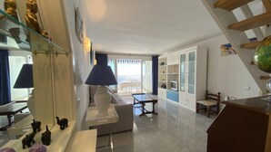 Un salon moderne avec une vitrine, une lampe blanche, un canapé, une table à manger et un escalier.