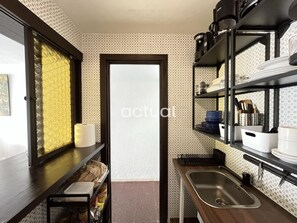 A compact kitchen with a built-in oven, a sink, and shelves for storage.