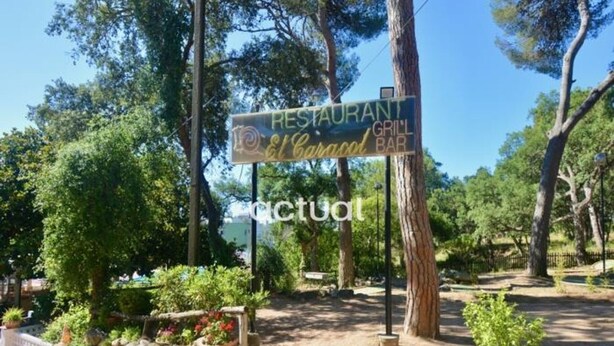 A restaurant sign with a grill bar, surrounded by trees and a stone wall. - Apartment with pool and Wi-Fi, near beach in Platja d'Aro (Platja d'Aro)