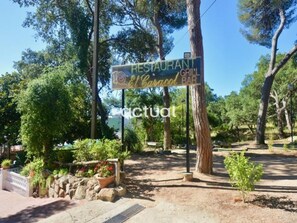 A restaurant sign with a grill bar, surrounded by trees and a stone wall. - Apartment with pool and Wi-Fi, near beach in Platja d'Aro (Platja d'Aro)