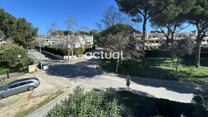 A street view with a parked car, trees, and residential buildings. - Apartment with pool and Wi-Fi, near beach in Platja d'Aro (Platja d'Aro)