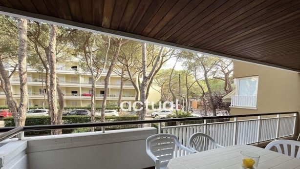 Un balcó amb taula i cadires, vista d'un edifici amb arbres i una barana.