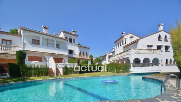 A swimming pool with stone tiles, surrounded by white buildings with arches and a clear blue sky. - Cosy townhouse, near beach, terrace, communal pool, WiFi and parking in Platja d'Aro (Platja d'Aro)