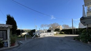 Vista callejera con un acceso enrejado, cielo despejado y edificios al fondo.