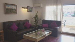 A living room with two dark leather sofas, a glass coffee table, a potted plant, and a painting on the wall. - 3-bedroom apartment, pool & parking, 350 m from the beach (Platja d'Aro)