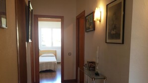 A hotel hallway with a bed in the background, a desk with a lamp, and framed pictures on the wall. - 3-bedroom apartment, pool & parking, 350 m from the beach (Platja d'Aro)