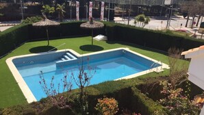A rectangular swimming pool with a blue interior, surrounded by well-maintained green grass and small trees. - 3-bedroom apartment, pool & parking, 350 m from the beach (Platja d'Aro)