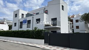 Un bâtiment moderne à deux étages, doté d’un toit plat, d’un balcon au deuxième étage et d’une entrée sécurisée par un portail.
