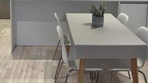 Un espace repas moderne avec une table rectangulaire, des chaises blanches et une plante en pot.