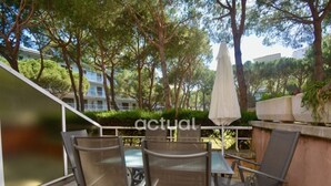 Une terrasse extérieure avec une table et des chaises, entourée d’arbres et agrémentée d’un parasol blanc.
