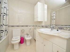 Un bagno con WC, bidet, lavandino e mobili.