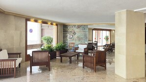 Um hall com móveis de madeira, um mural e plantas em vasos.