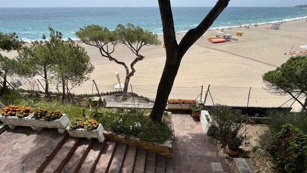Uma escadaria de pedra que leva a uma praia, com vista ampla para o oceano.