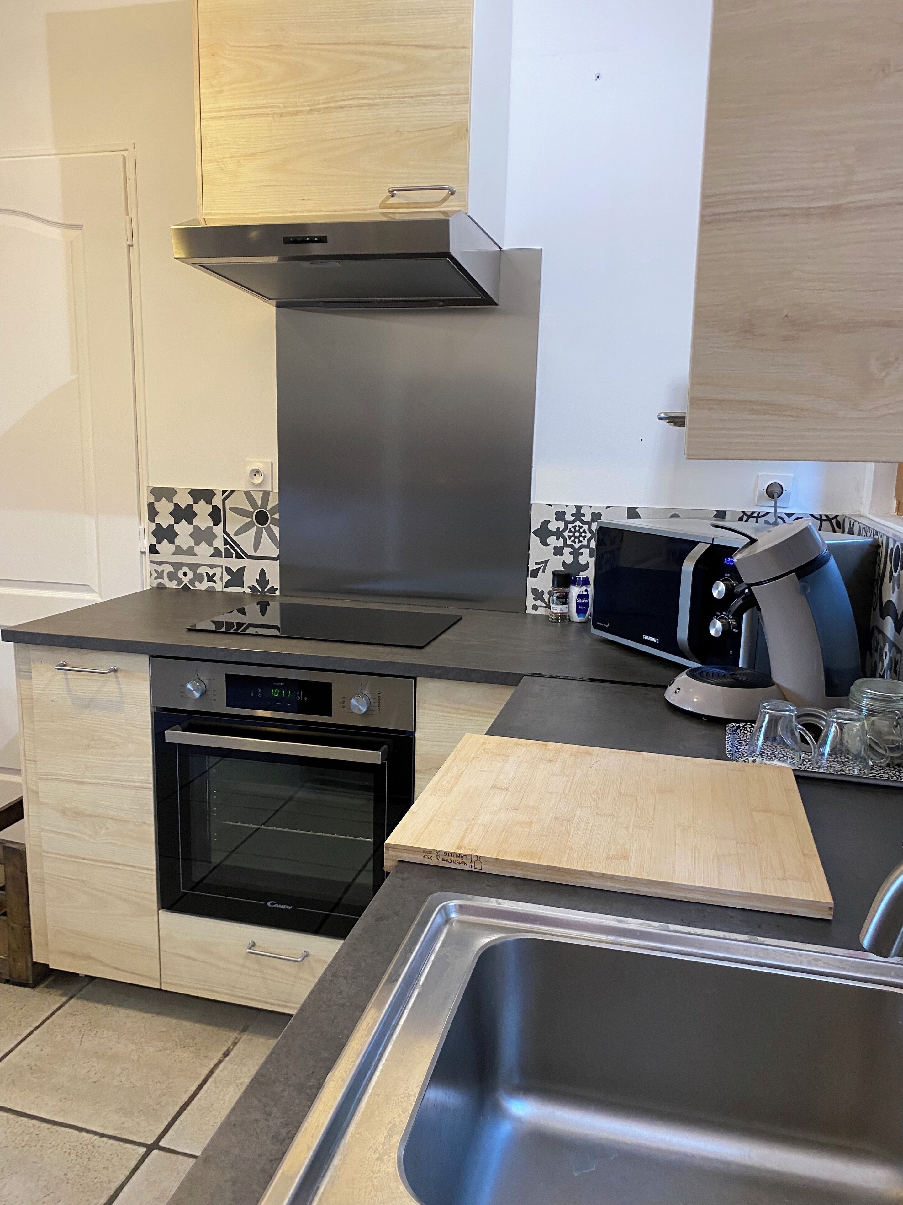 Een kleine keuken met een inbouwoven, een broodrooster en een RVS-spoelbak.