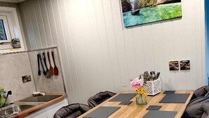 Une cuisine moderne avec une table en bois, des chaises noires et un tableau accroché au mur.