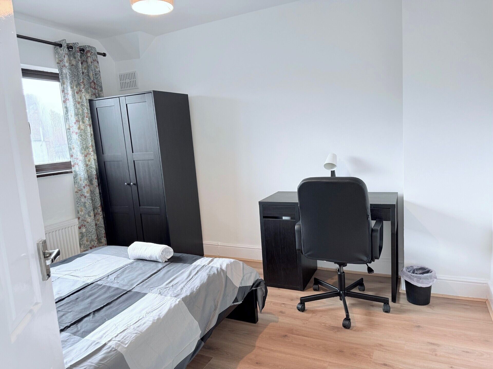 Une chambre à coucher comprenant un lit, un bureau, une chaise, une armoire et un radiateur.