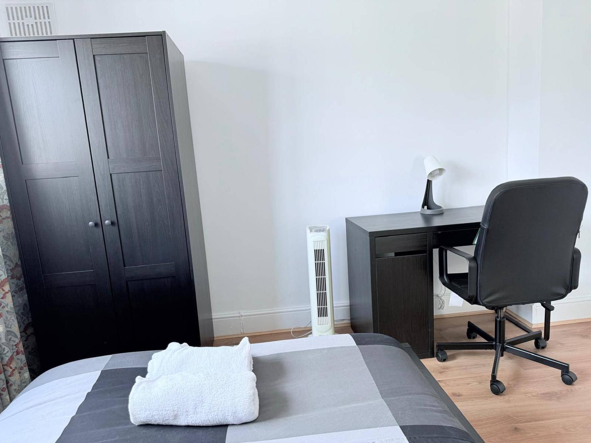 Ein Schlafzimmer mit einem Bett, einem Schreibtisch, einem Stuhl und einem Kleiderschrank.