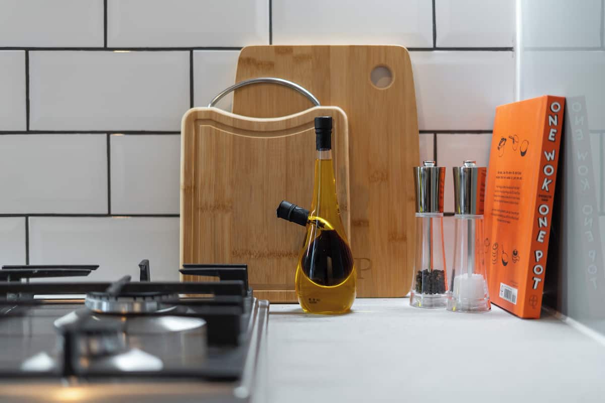 A kitchen counter with a cutting board, a bottle of oil, and a book titled "One Wok".