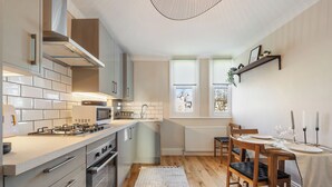 Een moderne keuken met een centraal eiland, een ingebouwde oven en een eethoek met een houten tafel en stoelen.