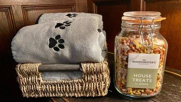 Una cesta tejida con un paño gris y un tarro etiquetado 'SIR WOODCHESTER'S HOUSE TREATS for DOGS'.