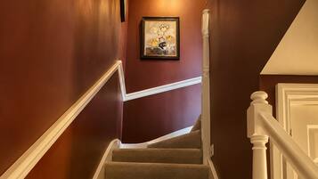 A staircase with carpeted steps, white handrails, and a wall-mounted picture frame.