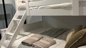 Ein Etagenbett mit einer Leiter, einer grünen Tagesdecke und zwei Handtüchern auf dem unteren Bett.