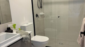Ein modernes Badezimmer mit Duschkabine aus Glas, einer weißen Toilette und einem Waschbecken mit Handtuch.