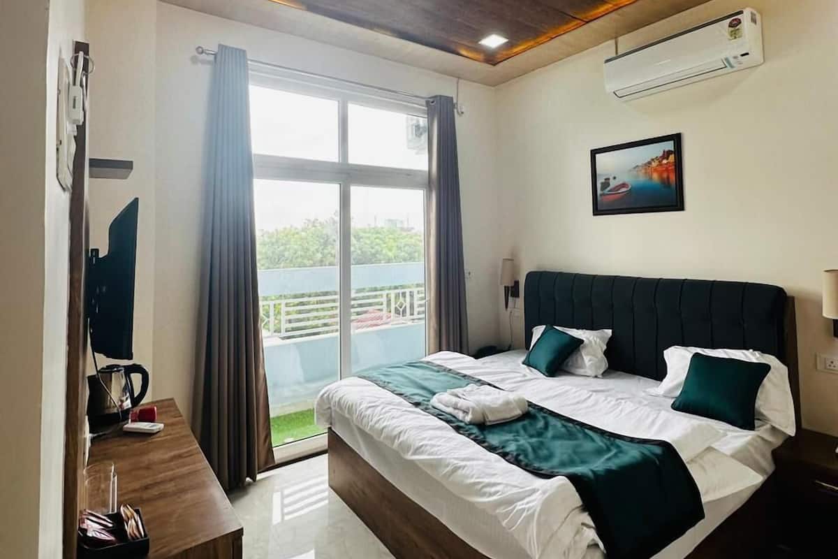A modern hotel room with a large bed, a ceiling fan, an air conditioning unit, a window with curtains, and a view of the outdoors.