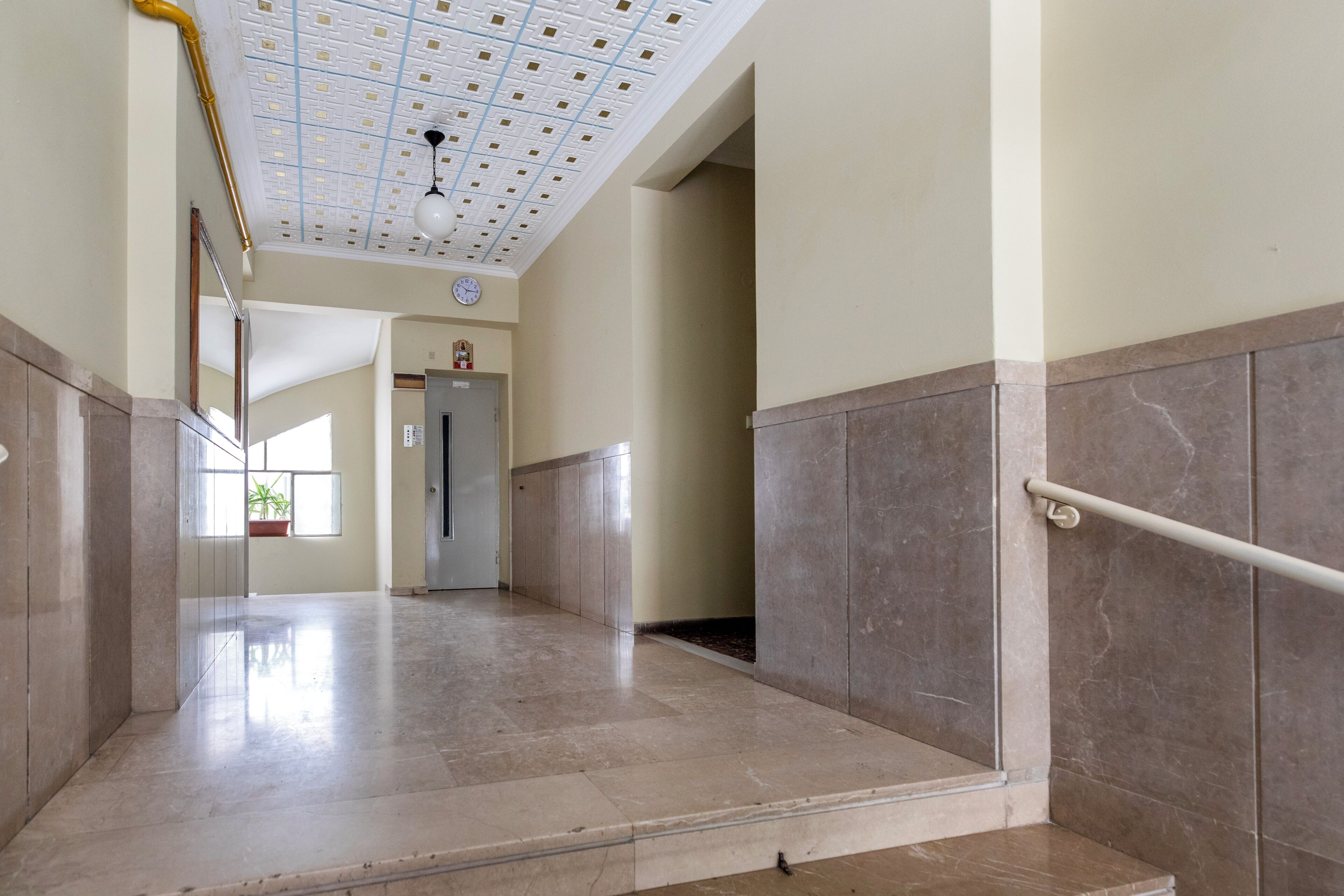 Un vaste hall d’entrée doté d’un sol en marbre, d’une main courante et d’un plafond orné d’un motif en réseau.