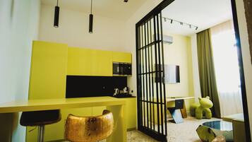 A modern kitchen with yellow cabinets, a black-framed glass door, and a bar area with stools.