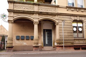 A building with ornate architectural details, including a decorative entrance with arches and columns, a black door, and a sign with a crest. - Design apartment with king-size beds & balcony (Pforzheim)