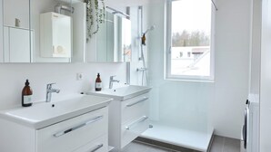 Moderni kylpyhuone, jossa on kaksi pesuallasta, suihku ja suuri ikkuna.