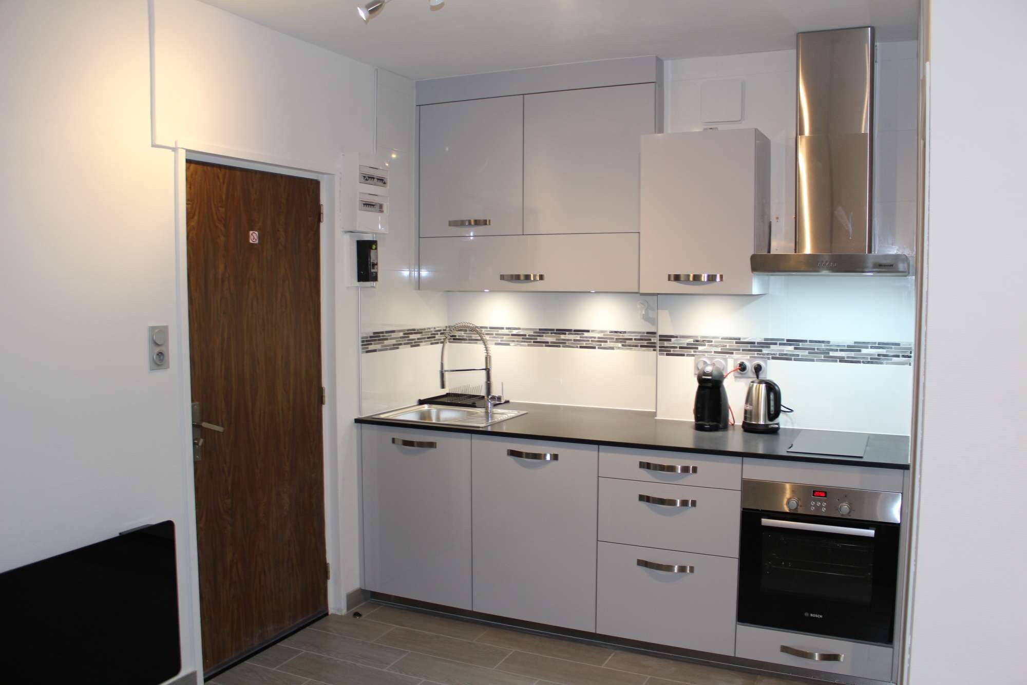 A modern kitchen with white cabinetry, a stainless steel oven, and a tiled backsplash.