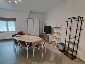 Ein Essbereich mit einem runden Tisch, Stühlen, einem Fernseher und einem Bücherregal.