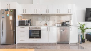 Een moderne keuken met witte kasten, roestvrijstalen apparatuur en een betegelde spatwand.