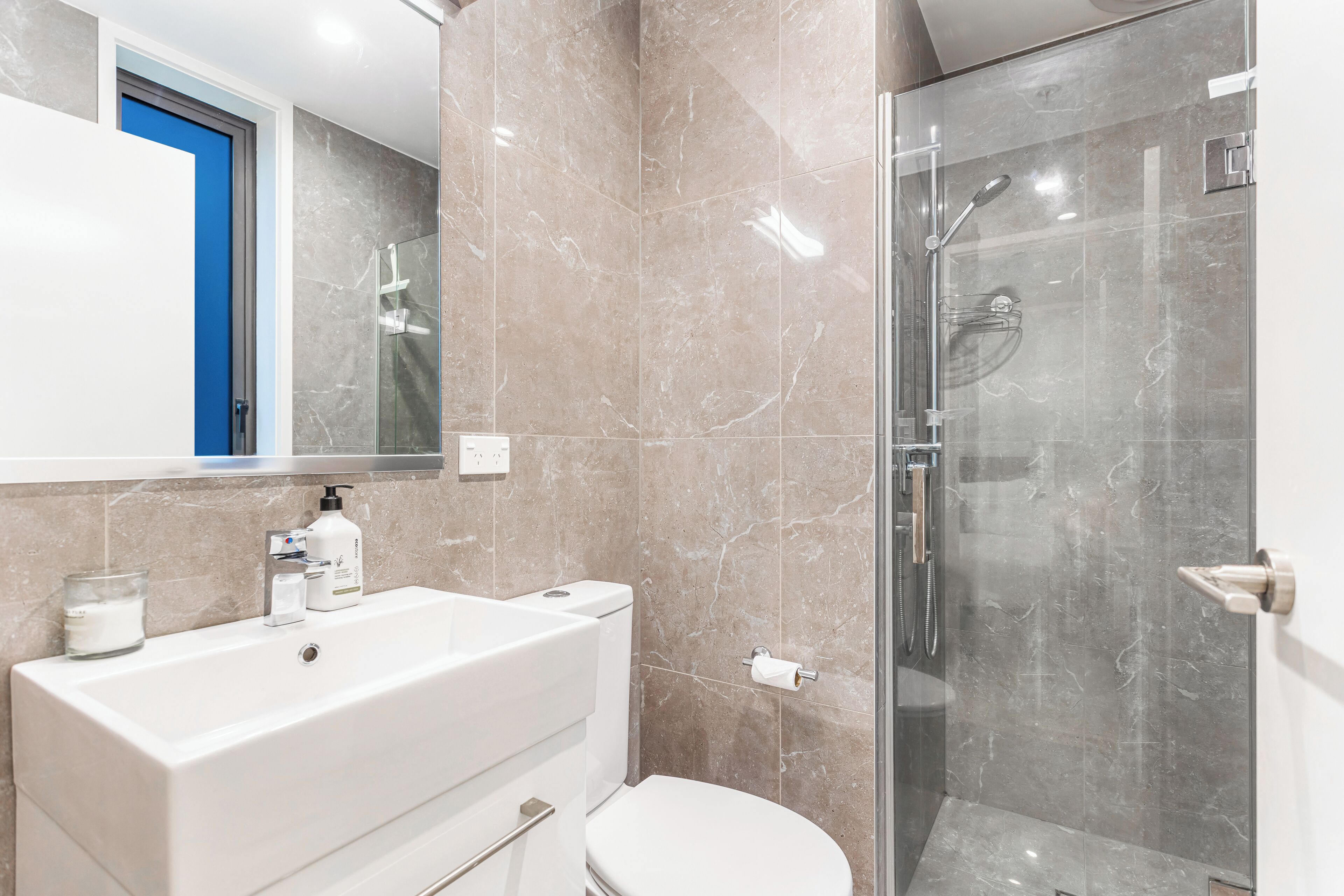 A bathroom with a large white sink, a toilet, and a glass-enclosed shower area.