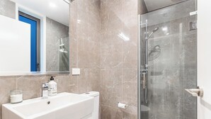 Een badkamer met een groot wit wastafel, een toilet en een douchecabine van glas.