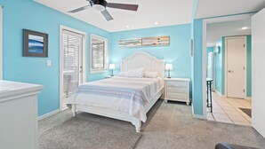 A bedroom with a bed, nightstands, a ceiling fan, and artwork on the walls.