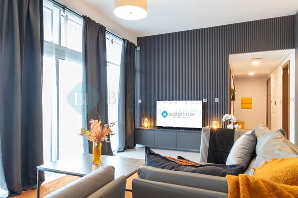 Un salon moderne avec un canapé, une table basse et un téléviseur à écran plat fixé au mur.