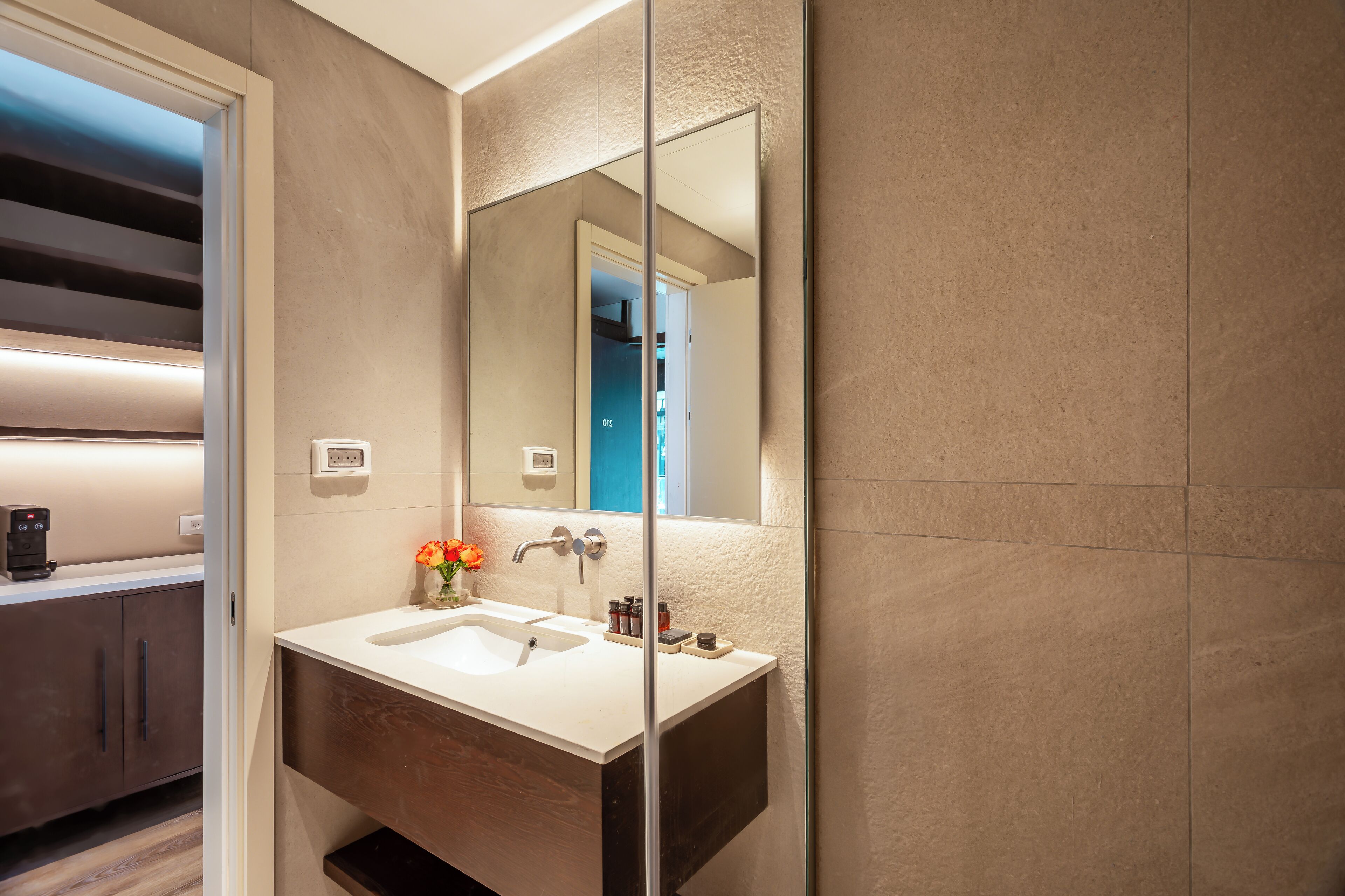 A modern bathroom with a large mirror, a sink, and a shower area.