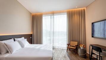Una habitación de hotel moderna con una cama grande, un escritorio, una silla y un televisor montado en la pared.