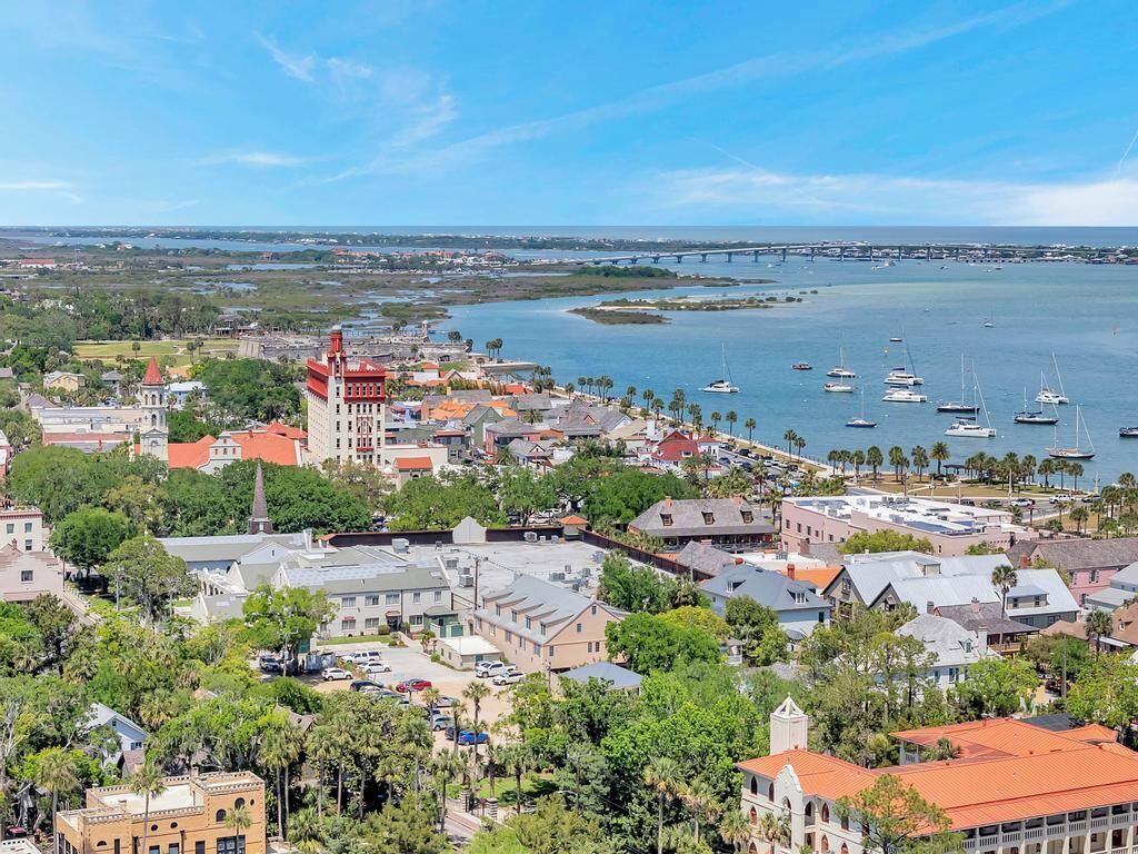 Un pueblo costero con un puerto deportivo, edificios históricos y un puente a lo lejos.