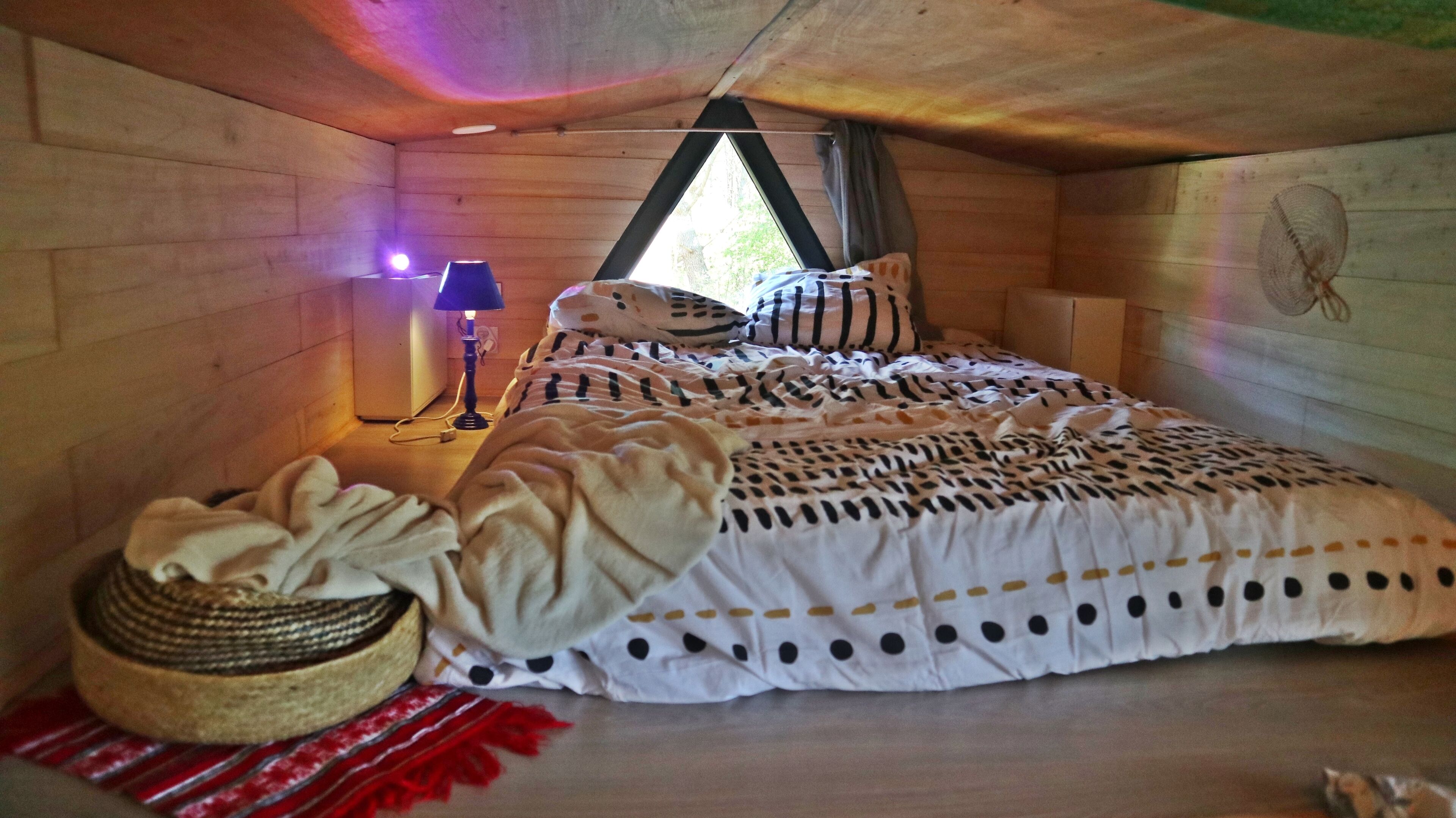 A cozy bedroom with a bed, a lamp, and a basket.