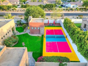 Una cancha de tenis con césped verde y un edificio al fondo.